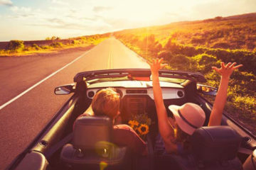 Happy Young Couple Driving Along Country Road in Convertible at